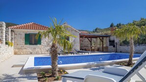 A stone building with a tiled roof, a swimming pool, lounge chairs, and a pergola. - House Irena (Postira)