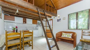 A rustic kitchen with wooden beams, a dining area with a wooden table and chairs, and a sofa with a cushion. - House Ivan (Bol)