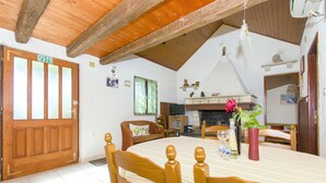 A dining area with a wooden table and chairs, a fireplace, and a view of the kitchen. - House Ivan (Bol)