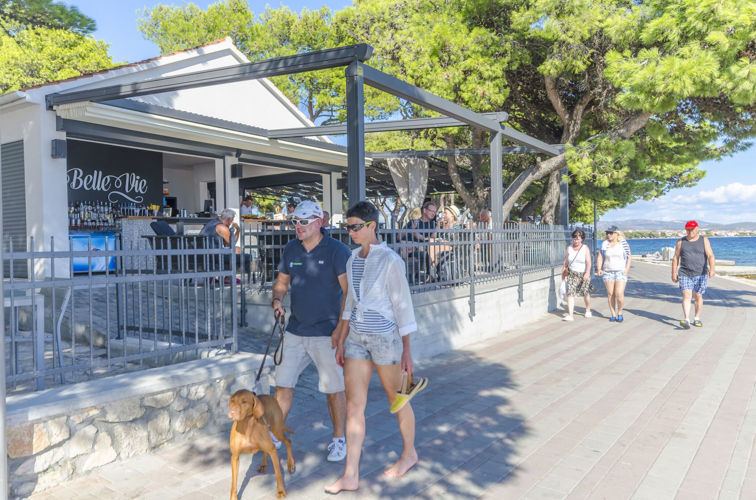 A waterfront bar named "Belle Vie" with outdoor seating and a stone wall.