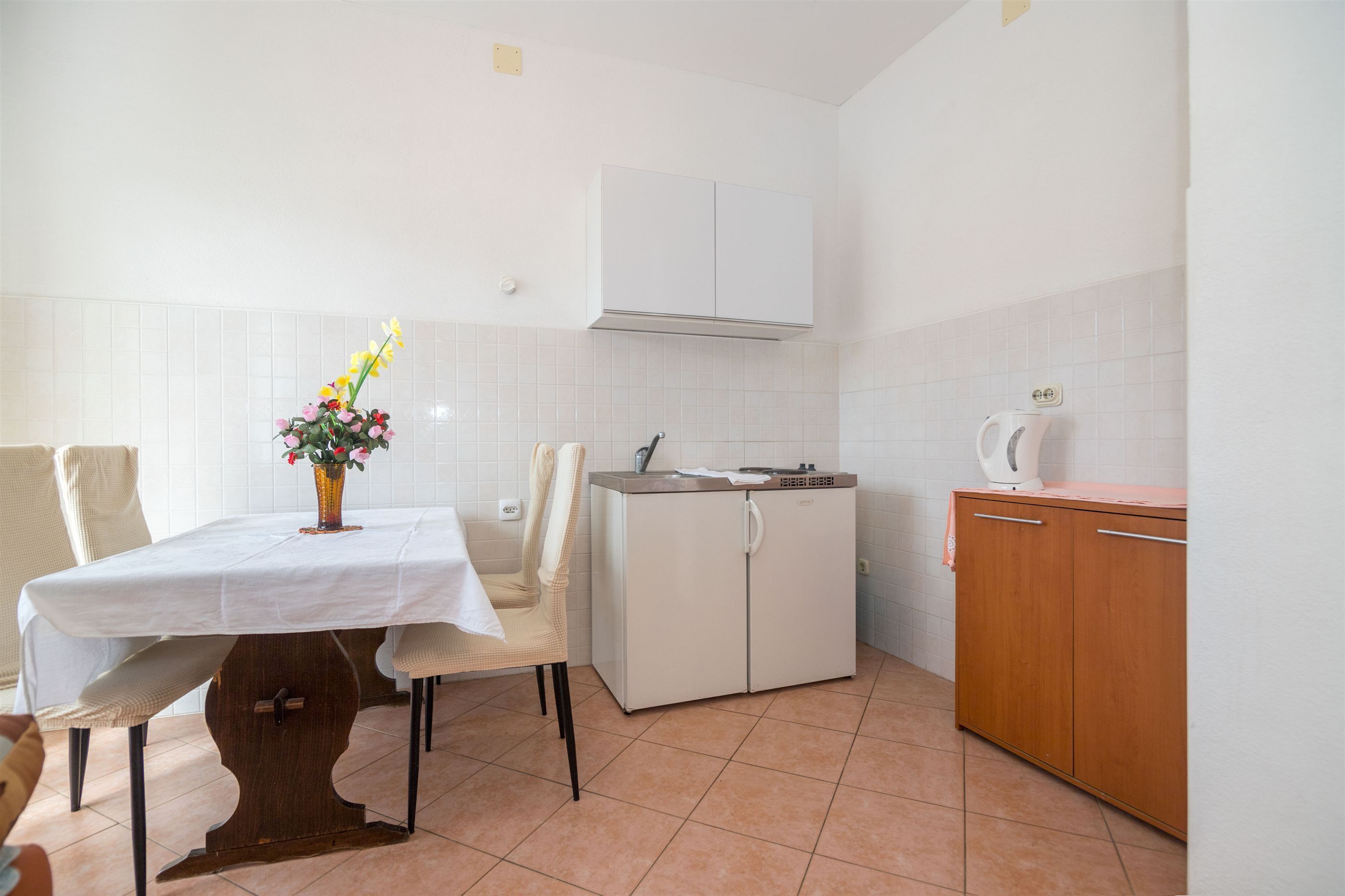 A kitchen with a dining table, chairs, a cabinet, and a microwave.