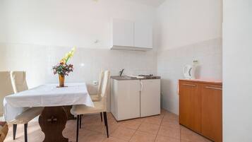 A kitchen with a dining table, chairs, a cabinet, and a microwave.