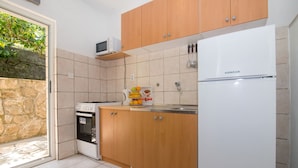 A kitchen with wooden cabinets, a white refrigerator, a microwave, and a stove. - Apartments Jelena (Sucuraj)