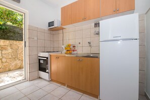 Eine Küche mit Holzausstattung, einem weißen Kühlschrank, einer Mikrowelle und einem Herd.