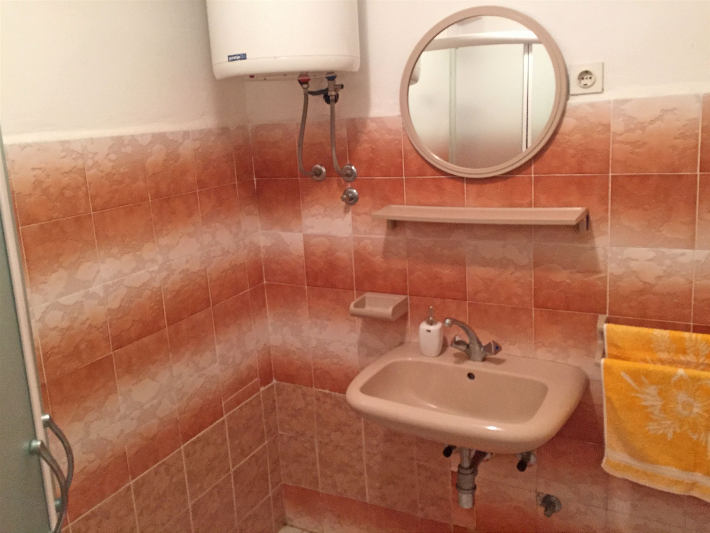 Un baño con lavamanos, espejo, toallero y retrete.