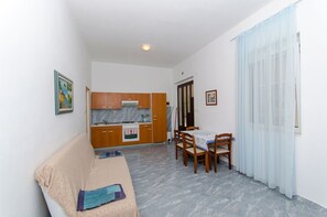 Un espacio habitable compacto con kitchenette, comedor y sofá.