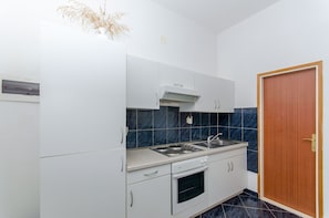 A kitchen with white cabinets, a stove, and a sink. - Apartments Ivanka (Vis)