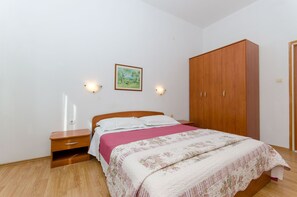 Un dormitorio con cama de madera, mesita de noche, armario y dos lámparas de pared.
