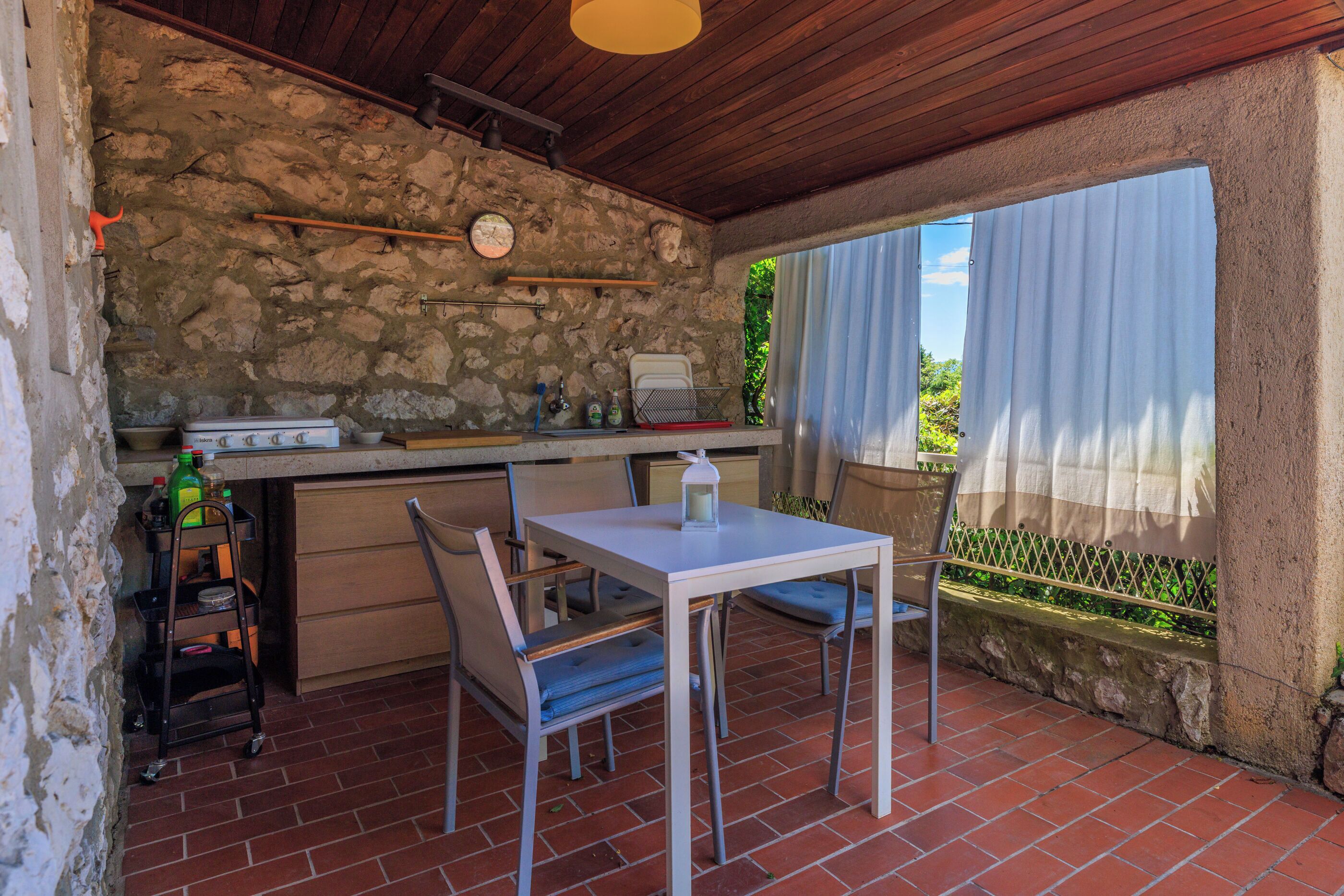 Une cuisine rustique aux murs en pierre, avec un plafond en bois et un coin repas comprenant une table et des chaises.