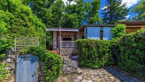A stone house with a stone staircase leading to a wooden door, surrounded by lush greenery. - House Bubble (Crikvenica)