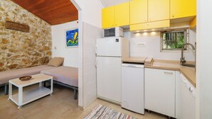 A compact kitchen with a refrigerator, a sink, and yellow cabinets. - House Bubble (Crikvenica)