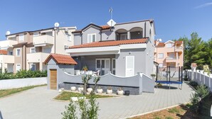 A modern two-story residential building with a tiled roof, a small front garden, and a paved driveway. - Apartment Lily With Pool Srima (Vodice)