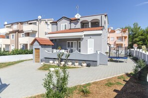 A modern two-story residential building with a tiled roof, a small front garden, and a paved driveway. - Apartment Lily With Pool Srima (Vodice)