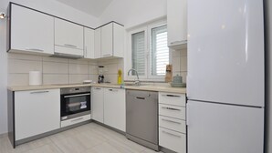 Eine moderne Küche mit weißen Schränken, einem Geschirrspüler, einem Backofen und einem Kühlschrank.