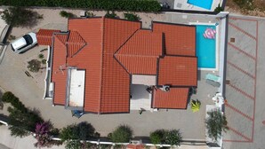 Ein Wohngebäude mit rotem Ziegeldach, Schwimmbad und Parkplatz.