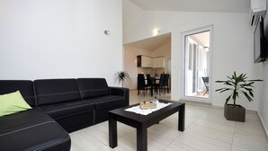 A modern living room with a black leather sofa, a wooden coffee table, and a potted plant. - Apartment Lily With Pool Srima (Vodice)