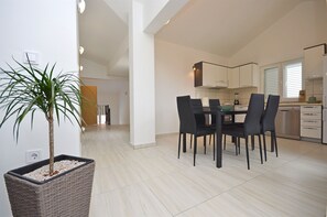 A modern kitchen with white cabinets, a dining table with chairs, and a potted plant. - Apartment Lily With Pool Srima (Vodice)