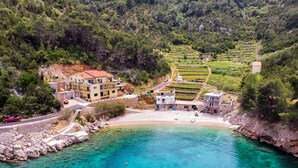 Un villaggio costiero con campi a terrazze, una spiaggia e edifici con balconi vista mare.
