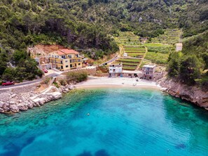Ein Küstendorf mit terrassenförmig angelegten Feldern, einem Strand und Gebäuden mit Balkonen mit Blick aufs Meer.