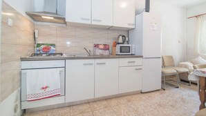 Una cucina con mobili bianchi, un fornello, un forno a microonde e un frigorifero.