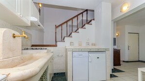 A kitchen with a built-in dishwasher, a gas stove, and a wooden staircase leading to another room. - House Merica (Trogir)