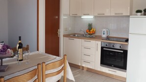 A modern kitchen with white cabinets, a built-in oven, and a sink. - Apartments Barac (Marina)