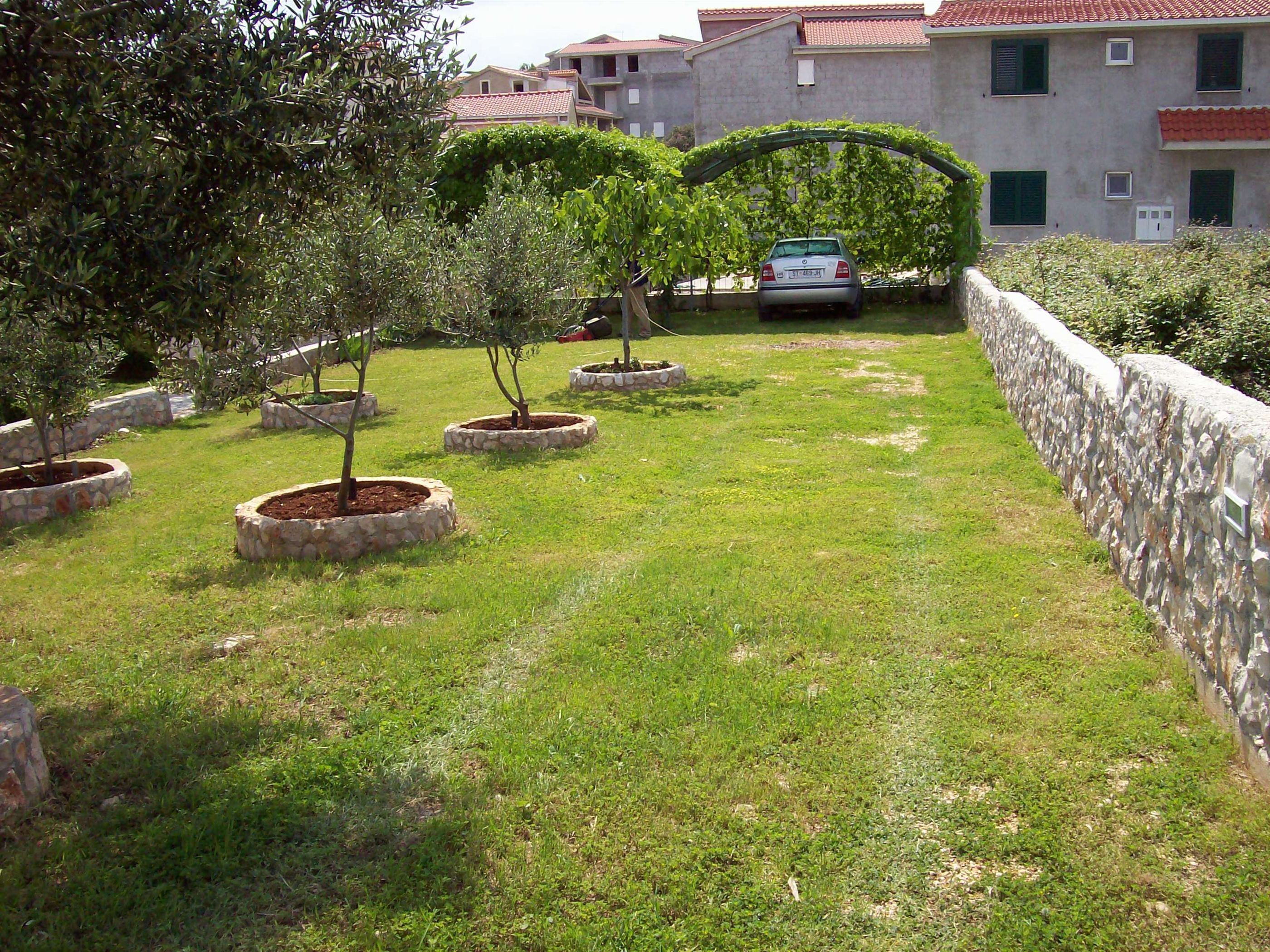Um jardim com vasos de pedra e um muro de pedra.