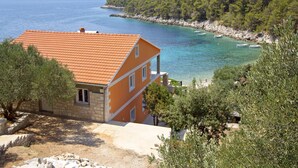 A coastal house with a tiled roof, a balcony, and a view of the sea. - Apartments Zeljko (Jelsa)