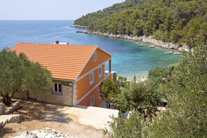 A coastal house with a tiled roof, a balcony, and a view of the sea. - Apartments Zeljko (Jelsa)