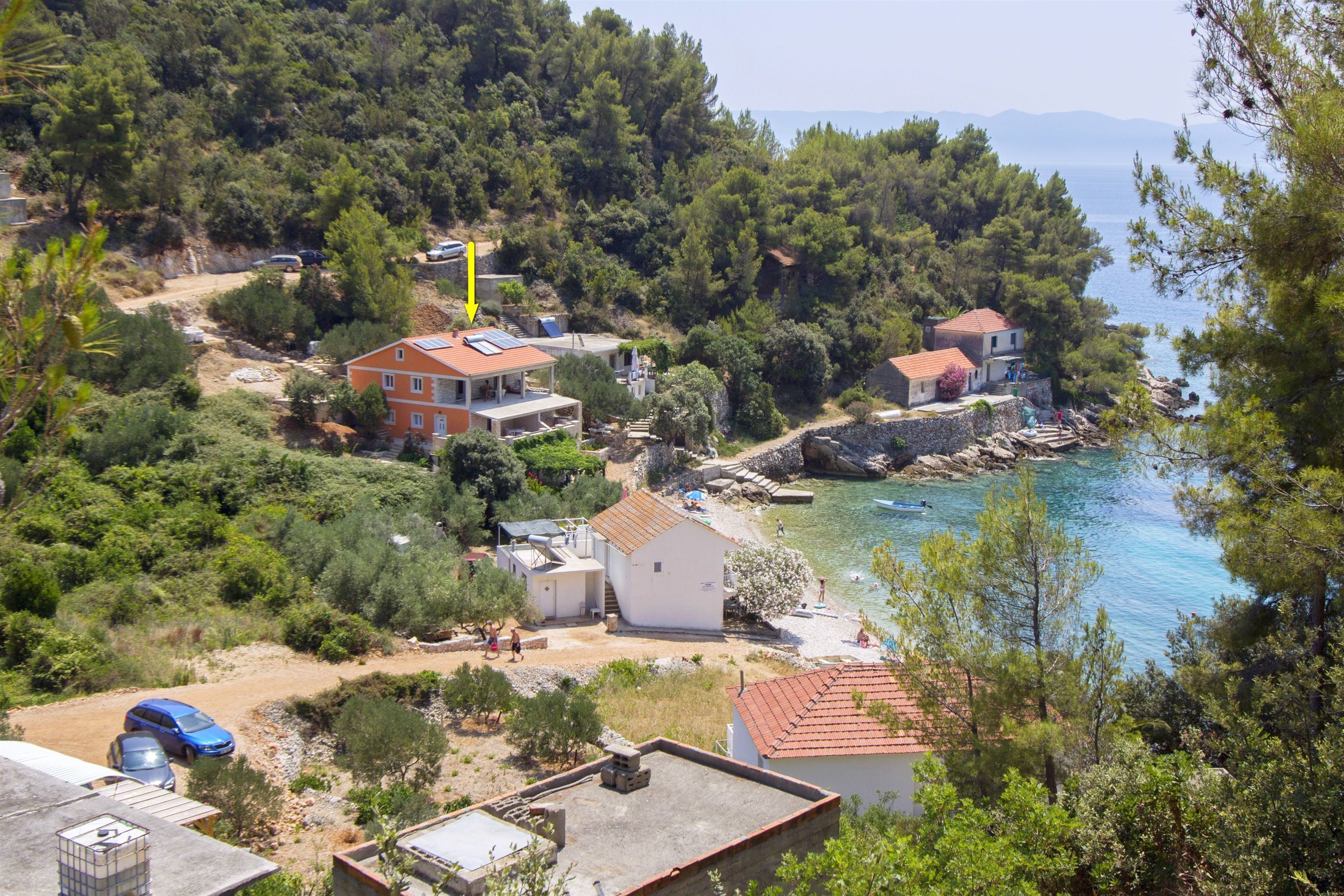 A coastal property with multiple buildings, a beach, and a rocky shoreline.