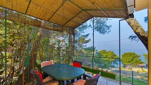Eine Außenpatio mit Tisch und Stühlen, umgeben von Grün und mit Blick auf eine schöne Aussicht.