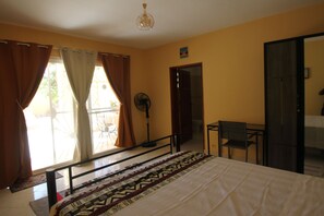 Une chambre à coucher avec un lit, un ventilateur, une table et une chaise.