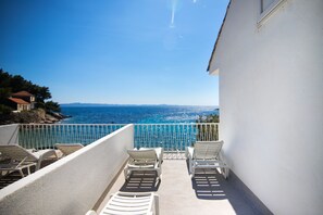 A balcony with white chairs and a view of the sea. - Apartments Robinzon Petar (Jelsa)