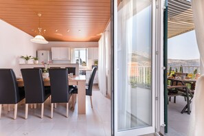 Une cuisine moderne avec des meubles blancs, un plafond en bois et un coin repas avec des chaises noires et une table en bois.