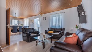 A modern living room with leather sofas, a glass coffee table, and a wooden ceiling. - House Marinka (Split)
