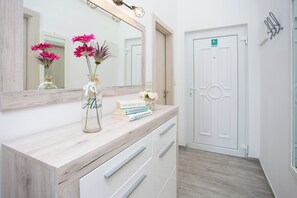 A bathroom with a wooden vanity, a large mirror, and a door with an accessibility sign. - Apartment Tatjana (Solta)