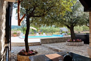 An outdoor pool area with lounge chairs, a stone patio, and a view of the surrounding landscape. - House Sweet Dreams (Selca)