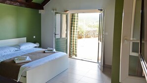 Un dormitorio con cama, ventana y puerta abierta que da a un balcón.