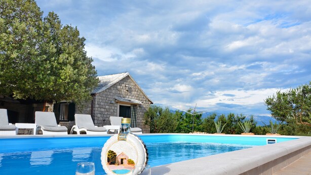 Zona de piscina con sillas de descanso, un edificio de piedra y cielo despejado.