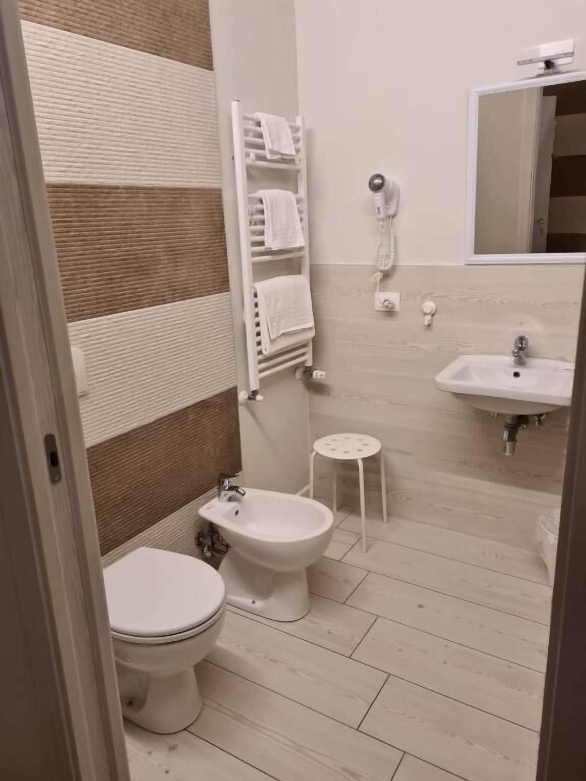 Un baño con inodoro, bidé, toallero y lavamanos.