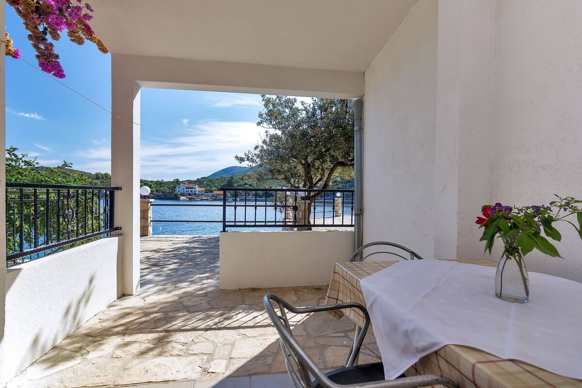 A balcony with a table, chairs, and a vase of flowers.