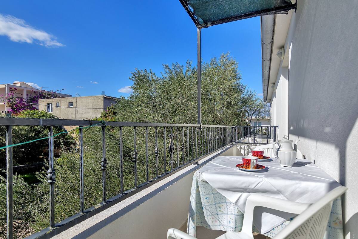 A balcony with a table set for two, a chair, and a white wall.