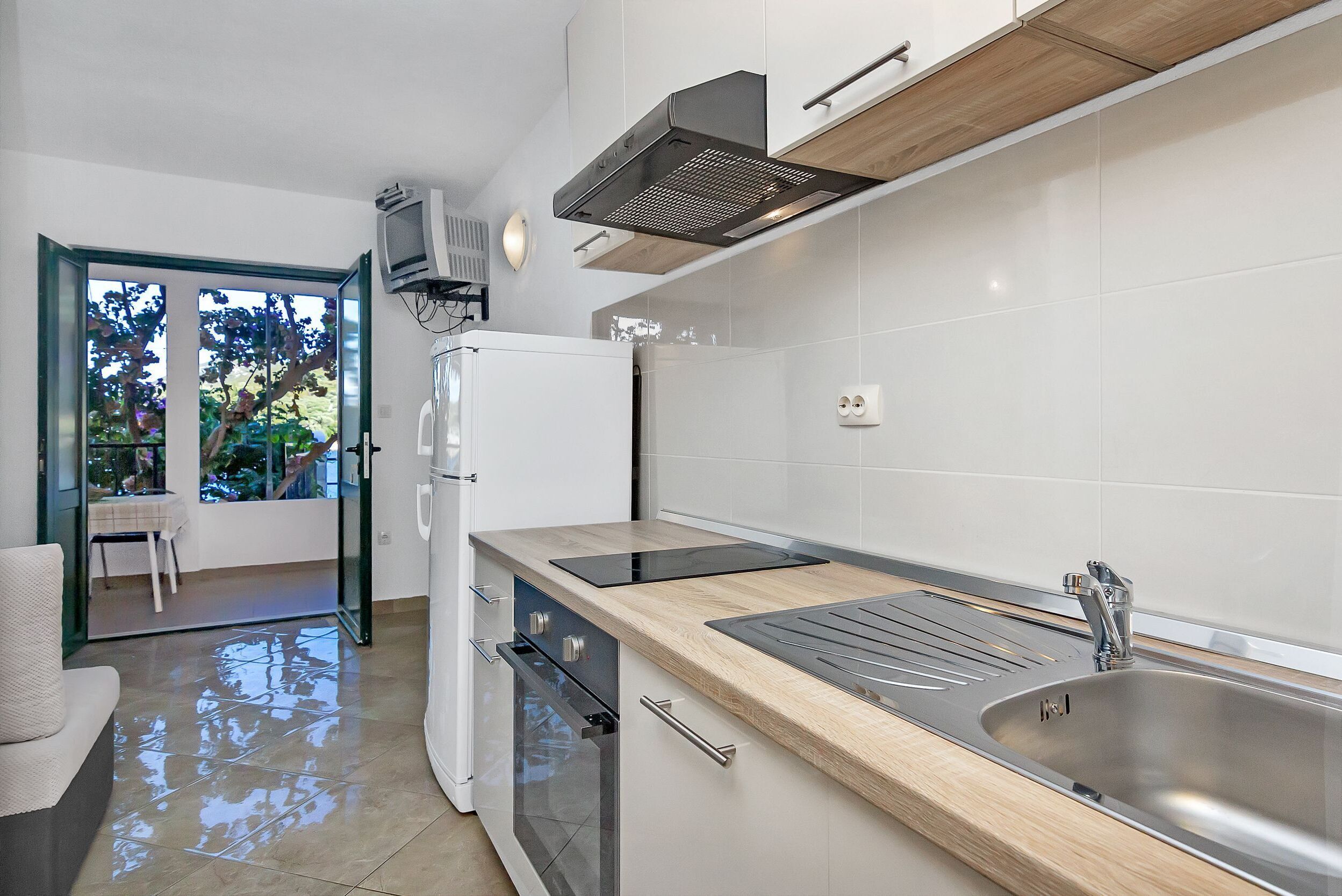 Een moderne keuken met een roestvrijstalen spoelbak, een houten aanrecht en een inbouwoven.