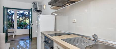 Een moderne keuken met een roestvrijstalen spoelbak, een houten aanrecht en een inbouwoven.
