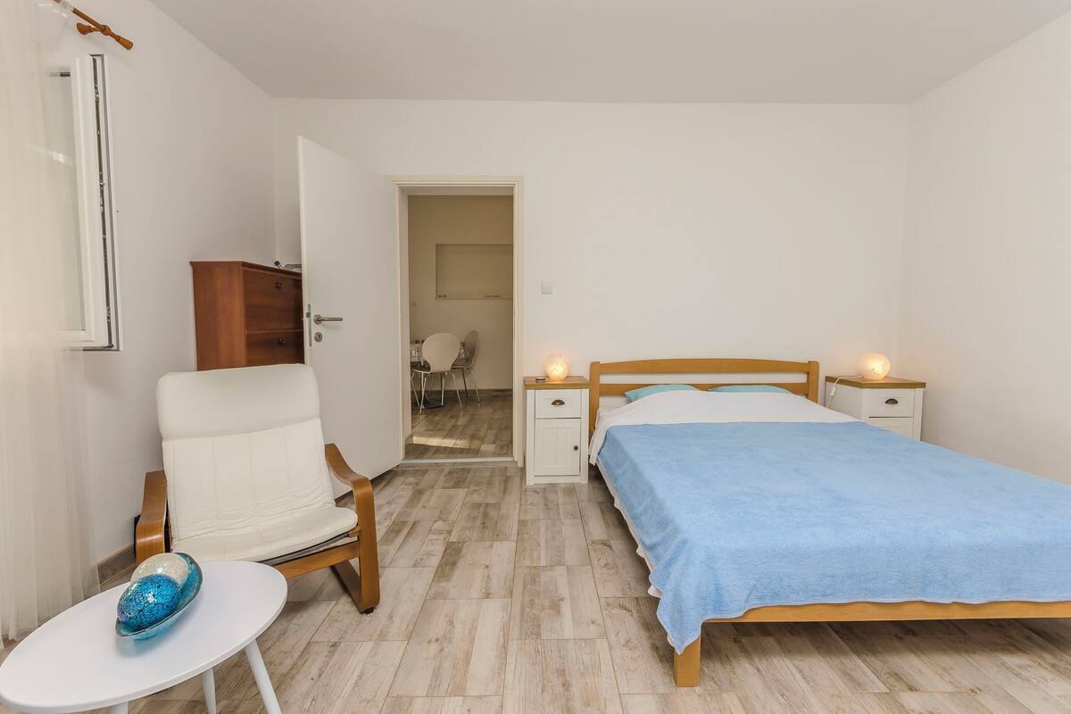 A bedroom with a bed, bedside tables, a chair, a small table, and a wardrobe.