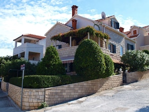 A two-story house with a stone facade, a tiled roof, and a satellite dish. - Apartments Etica (Postira)