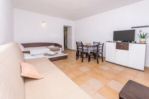 Ein modernes Wohnzimmer mit Sofa, Esstisch und Fernseher.
