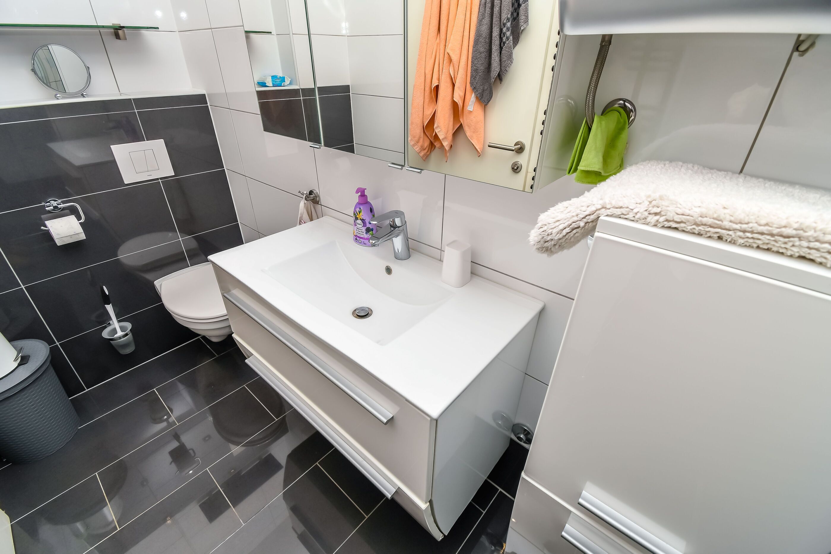 A modern bathroom with a white sink, a toilet, and a mirror.