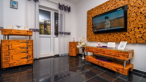 A modern room with a wooden dresser, a television mounted on a textured wall, and a vase with flowers. - Apartment Cicko (Trogir)