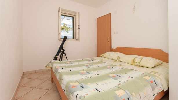 A bedroom with a bed, a window, a door, and a tripod. - House Vela Lozna (Postira)